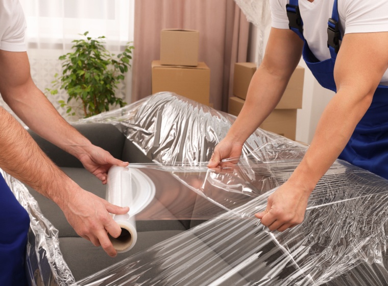 movers wrapping sofa in plastic